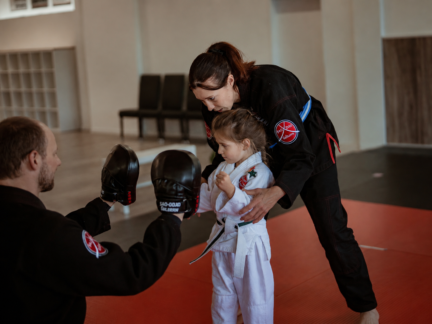 Trainerin begleitet ein kleines Kind beim Training an den Schlagpolstern im SAO-DOJO Geldern